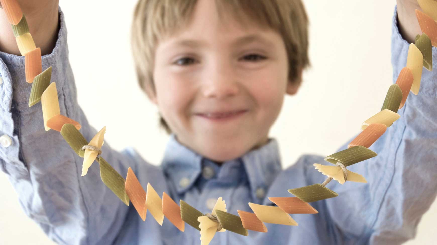 Boy stringing macaroni necklace